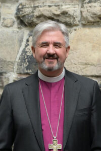 Archbishop Shane Parker in clerical attire, photographed against a stone background